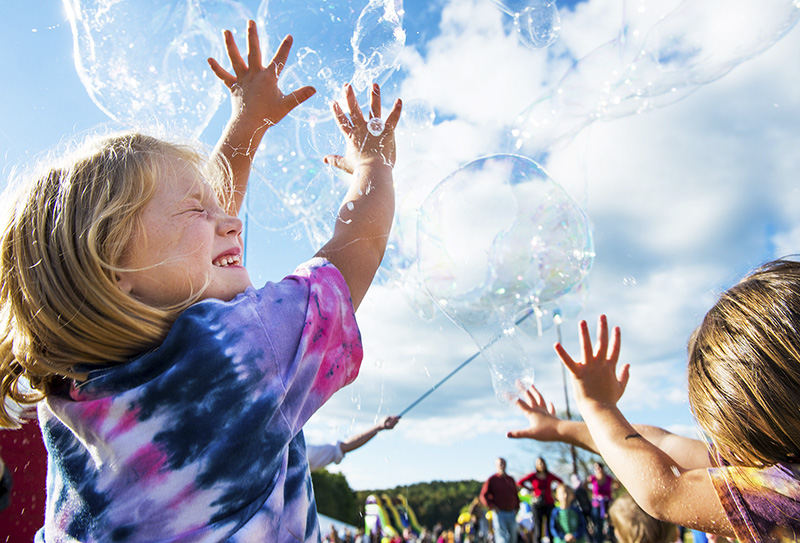 Feature - 2nd place - Nora Martin, 6, (left) of Cincinnati, enjoys popping numerous large bubbles created by John Gradwohl Jr., also known as Professor Phineas T. Bubblemaker, during his show at the Pawpaw Festival held at Lake Snowden near Albany. (Isaac Hale / Ohio University)