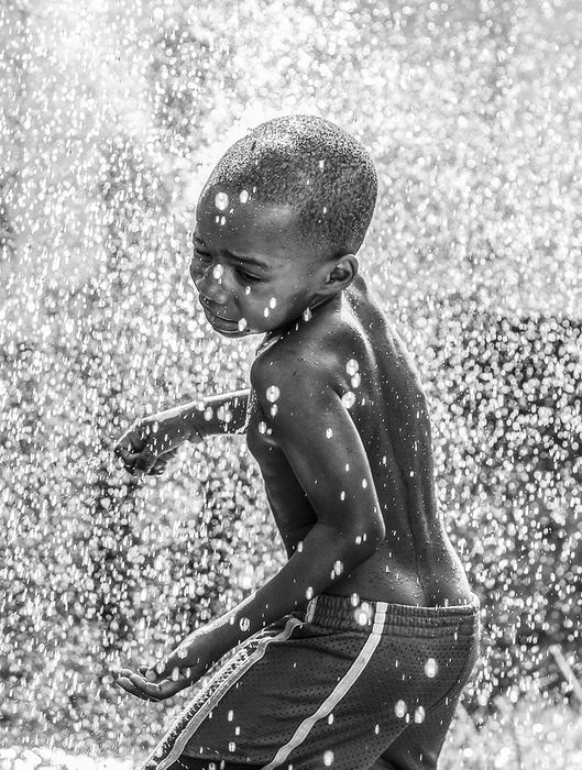 Feature - HM - Germiah Wells, 3,  gets hit with water from a garden hose as he and his sister  Geniah Wells, 7, cool off at their Spring Street home. (Andy Morrison / The (Toledo) Blade)