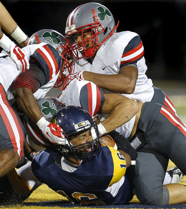 Sports - 1st place - Whitmer High School player Shue Sanders (16) has his helmet twisted as he is tackled by Toledo Central Catholic players Stephon Campbell (7) Charles Smith (3) and Richard Jackson (37) during the second quarter at Whitmer High School. (Andy Morrison / The (Toledo) Blade)