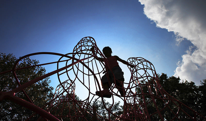 Feature - 2nd place - Against a blazing sun and an almost cloudless sky, Zayd Muhammad, 4, climbs a tower at the Kwansaa Playground at English Park in Columbus on September 8, 2015.  He was busy climbing while his mother Brittany Thompson sat nearby keeping an eye out for him.   (Chris Russell / The Columbus Dispatch )