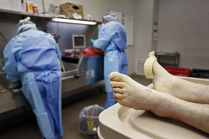 AGeneral News - 2nd place - With the help of investigator and autopsy assistant Renee Rogers (left) Dr. Jeff Lee, a forensic pathologist for the Licking County Coroner's office, examines internal organs while performing an autopsy of a 42-year-old man in Newark.  (Adam Cairns / The Columbus Dispatch)