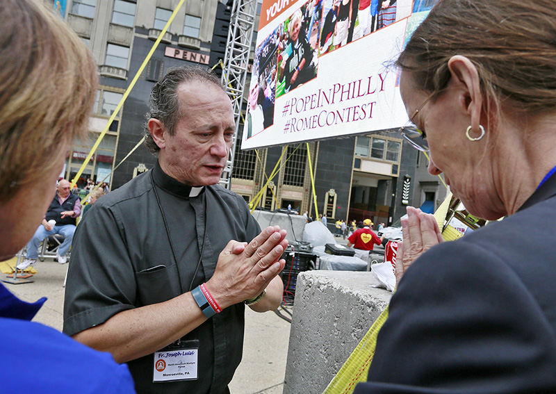 Story - 2nd place - Father Joseph Luisi of Monroeville, Pa., prays with two women prior to the Papal Mass on the Benjamin Franklin Parkway. As many as a million or more visitors were estimated to have attended.  (Barbara J. Perenic / The Columbus Dispatch)