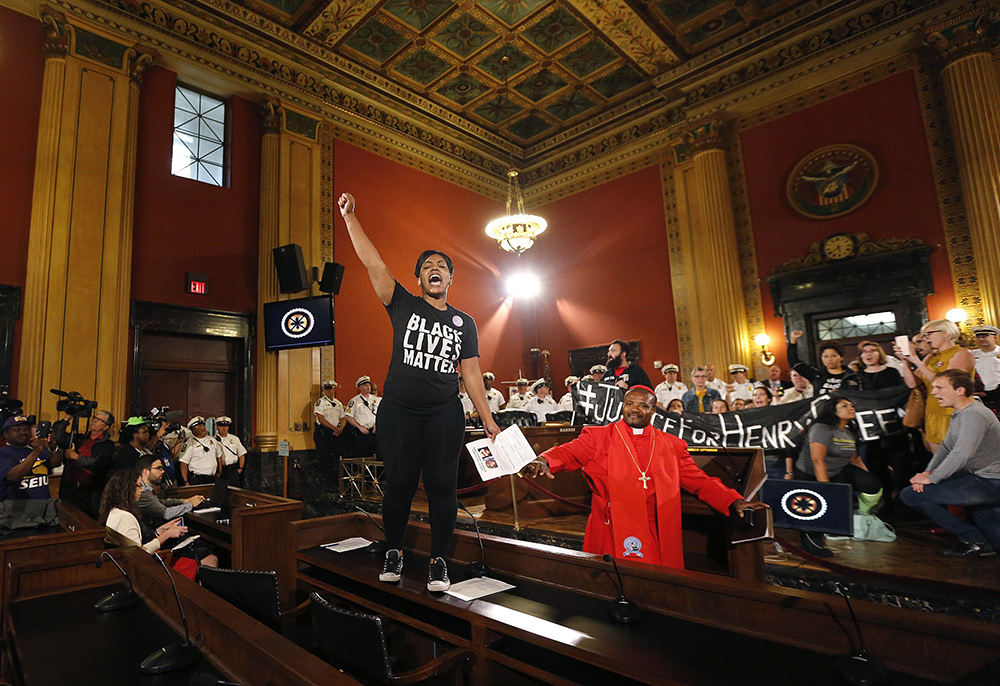 General News - 1st place - Hana Abdur-Rahim raises her fist while standing on a desk after protesters interrupted the Columbus City Council meeting. Dozens of demonstrators protesting the fatal police shooting of 13-year-old Tyre King brought the meeting to a halt as they called for an independent investigation.  (Jonathan Quilter / The Columbus Dispatch)