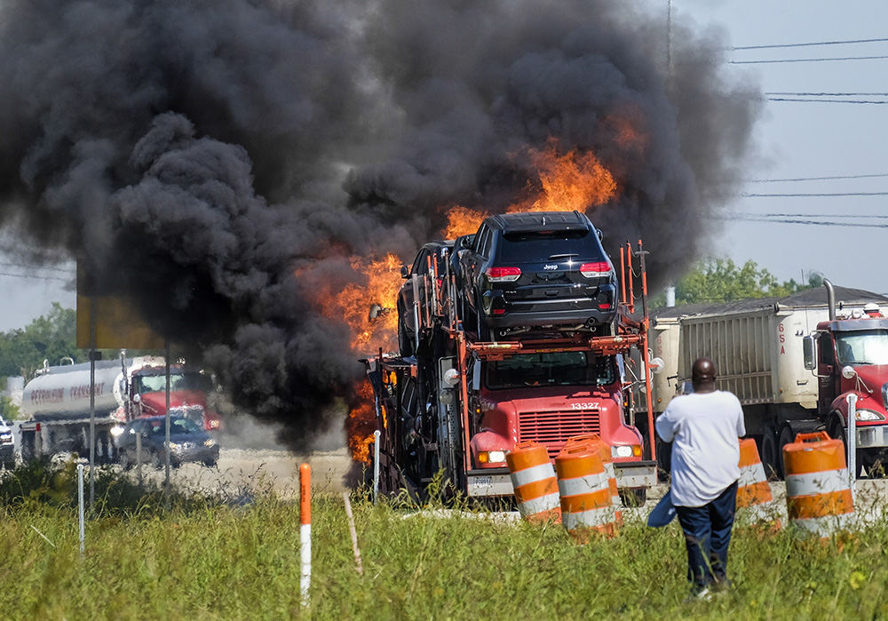 Spot News - 1st place - The driver of a car carrier watches as his load of Jeep Grand Cherokees go up in flames on I-75 north of Monroe, Michigan.    (Andy Morrison / The (Toledo) Blade)