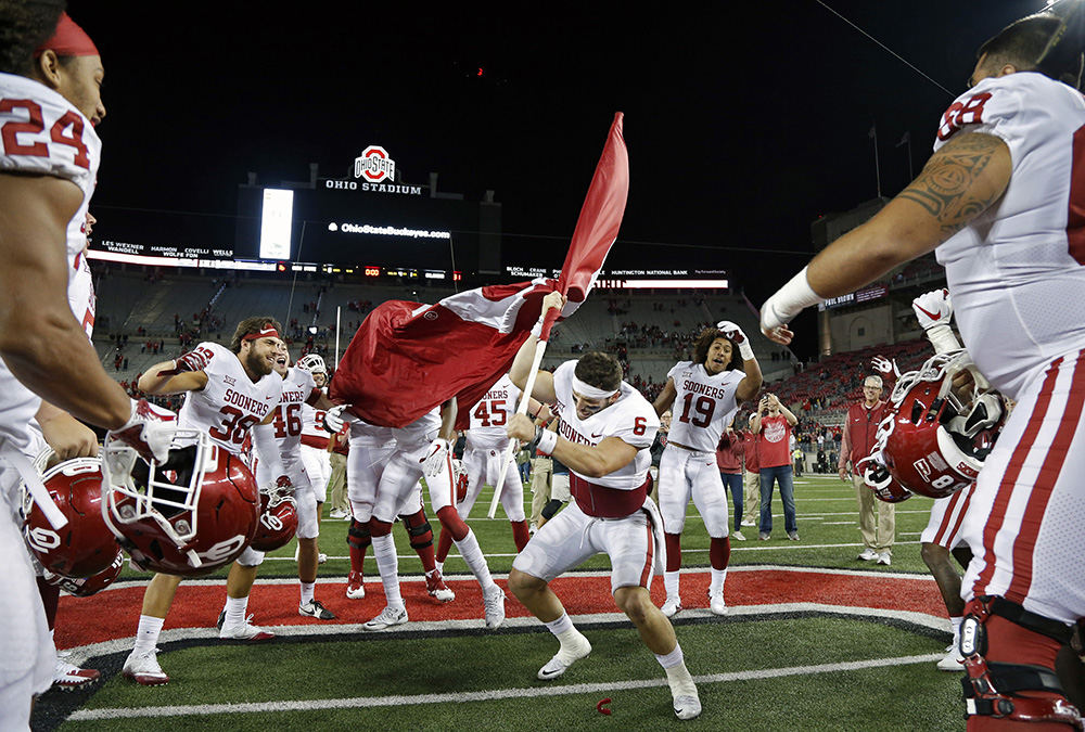 Sports Feature - 2nd place - Oklahoma quarterback Baker Mayfield (6) plants the Sooner flag in the Ohio State logo at midfield after beating Ohio State 31-16 at Ohio Stadium in Columbus.  (Kyle Robertson / The Columbus Dispatch)