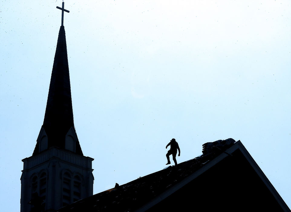 Feature - 2nd place - A worker is silhouetted against the sky as he works on the roof the First Lutheran Church on West High Street in Springfield. (Bill Lackey / Springfield News-Sun)