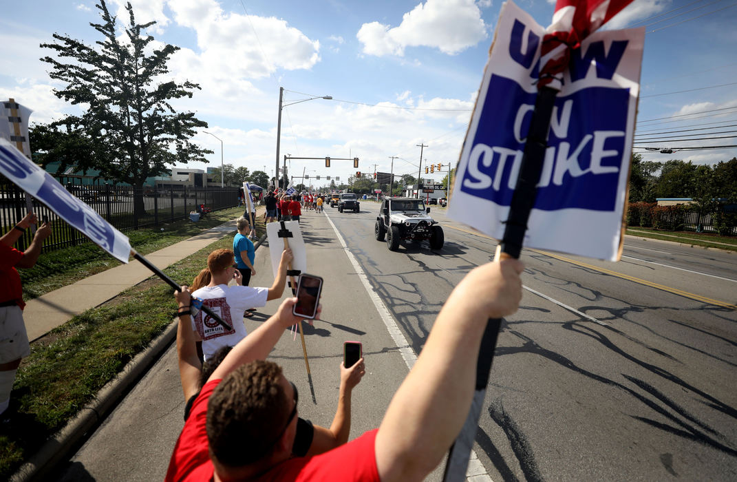 General News - 3rd placeLeroy Gallagher, an assembly worker on strike raises his picket sign and his American flag as a convoy of mostly Jeeps and Corvettes passes in front of striking workers along Alexis Road at the General Motors Powertrain Plant in Toledo. The event, which started at Wheelin' on the Rocks, was a showing of solidarity for the striking GM workers.  (Kurt Steiss / The Blade)