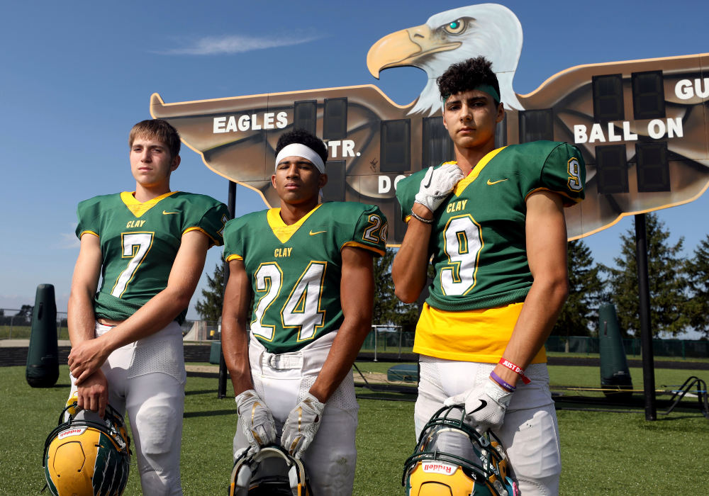 Portrait - HMClay football players (from left) Logan Heintschel, Jordan Pettaway and Andrew Collins pose for a group portrait during football practice at Clay High School in Oregon, Ohio. (Kurt Steiss / The Blade)