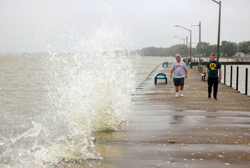 Feature - 1st place - A large wave crashes into the pier as Tim Nadolny walks on the pier with his 17-year-old son, Timmy from Erie, Mich., on a rainy and windy day along Lake Erie in Luna Pier, Michigan. (Kurt Steiss / The Blade)