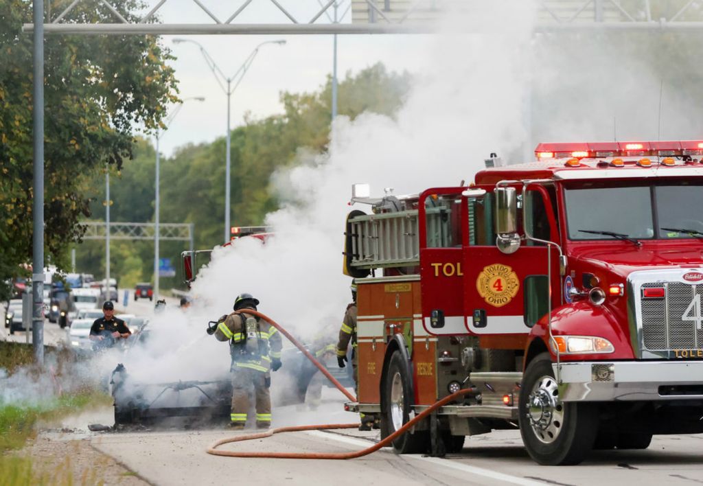 Spot News - 2nd place - A Toledo firefighter extinguishes a car fire at I-475 by the Corey Road exit near Toledo. (Kurt Steiss / The Blade)