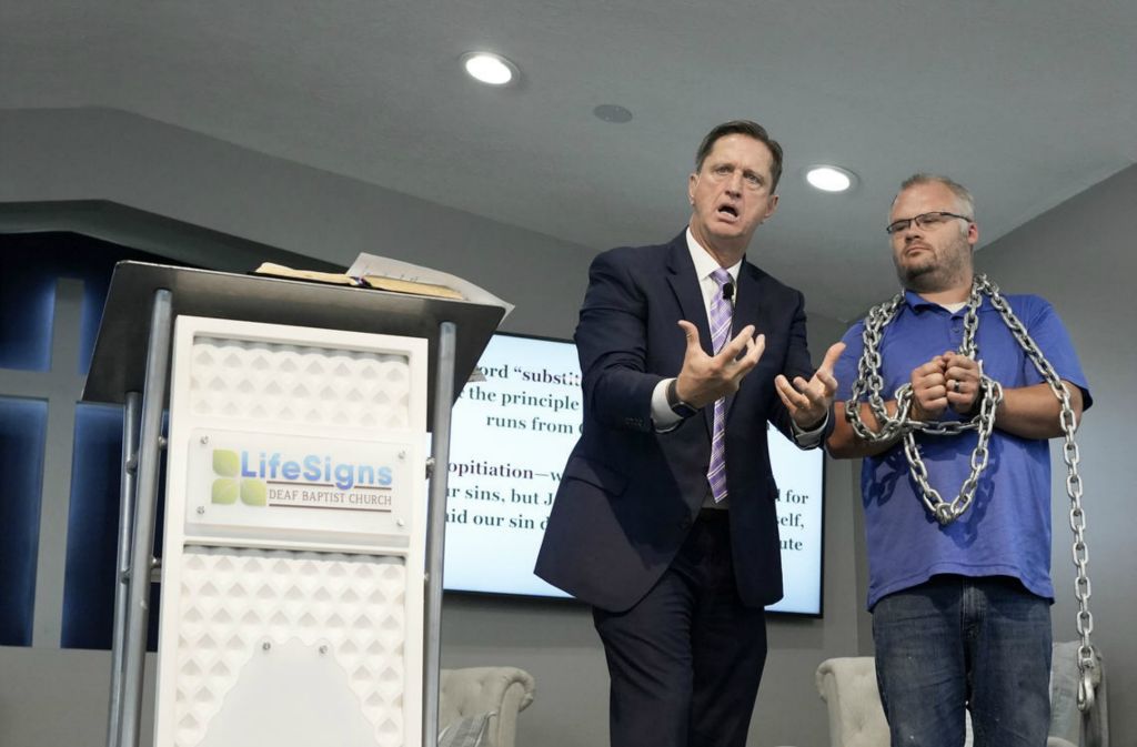 Story - 1st place - Pastor Scott Crabtree (left) makes a point about Jesus by hanging a heavy chain on parishioner Ryan Fields while leading services at LifeSigns Deaf Baptist Church. Crabtree lives with a 95% hearing loss.  (Barbara J. Perenic / The Columbus Dispatch)