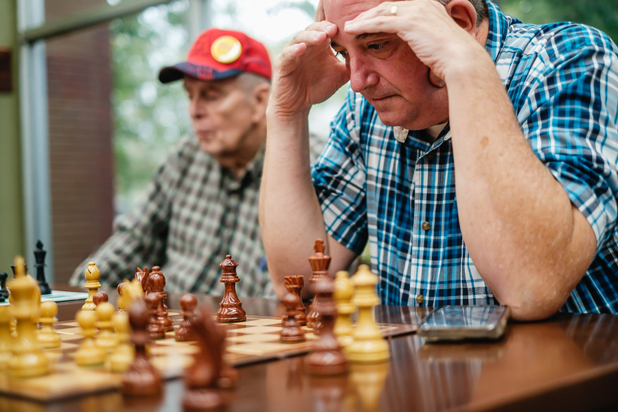 Feature - HM - Bill Houghlan (right) of Dover, ponders over a chess game at the Dover Public Library. The chess club meets in the food court of the New Towne Mall in New Philadelphia. The club is informal and all are welcome. (Andrew Dolph / The Times Reporter)