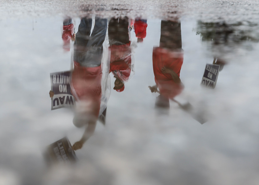 General News - HM - United Auto Workers member Michael Oakley (bottom left) waves one of two signs at motorists on southbound I-75 while picketing in the rain with Team 24 outside a truck entrance to Stellantis Toledo Assembly Complex in Toledo. (Isaac Ritchey / The Blade)