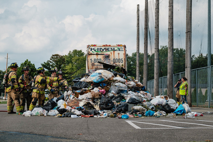 Spot News - HM - Dover firefighters sift through a pile of trash that was on fire inside a Kimble trash truck at Dover City Park. The truck was driven to the parking lot nearest North Wooster Avenue and subsequently emptied of its contents to be extinguished by firefighters. (Andrew Dolph / The Times Reporter)