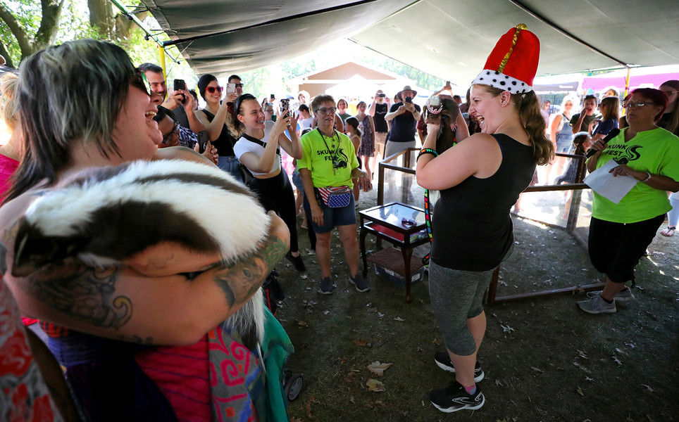 General News - 3rd place - Shannon Horvat of Euclid (right) and her five-year-old chocolate skunk Flash play up to the crowd after being crowned this year’s Skunk Fest King during the annual gathering of skunk owners at South Central Park in North Ridgeville. (Jeff Lange / Akron Beacon Journal)