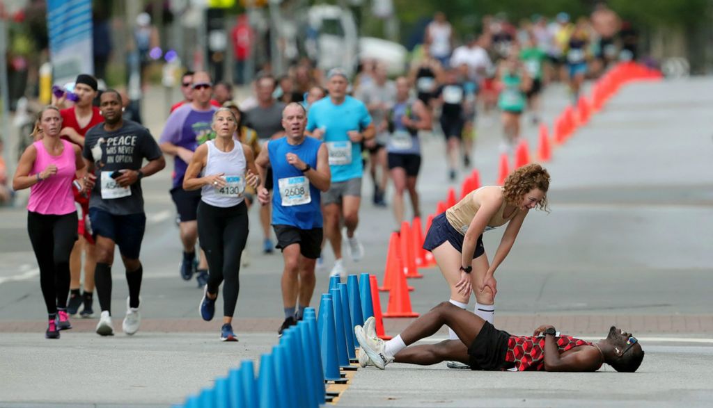 Sports Feature - 3rd place - Madison Gajarsky of Broadview Heights checks on Seyram Wisdom Djobokou Koumako of Cleveland after he took a spill in the homestretch of the 2024 Akron Half Marathon. (Jeff Lange / Akron Beacon Journal)