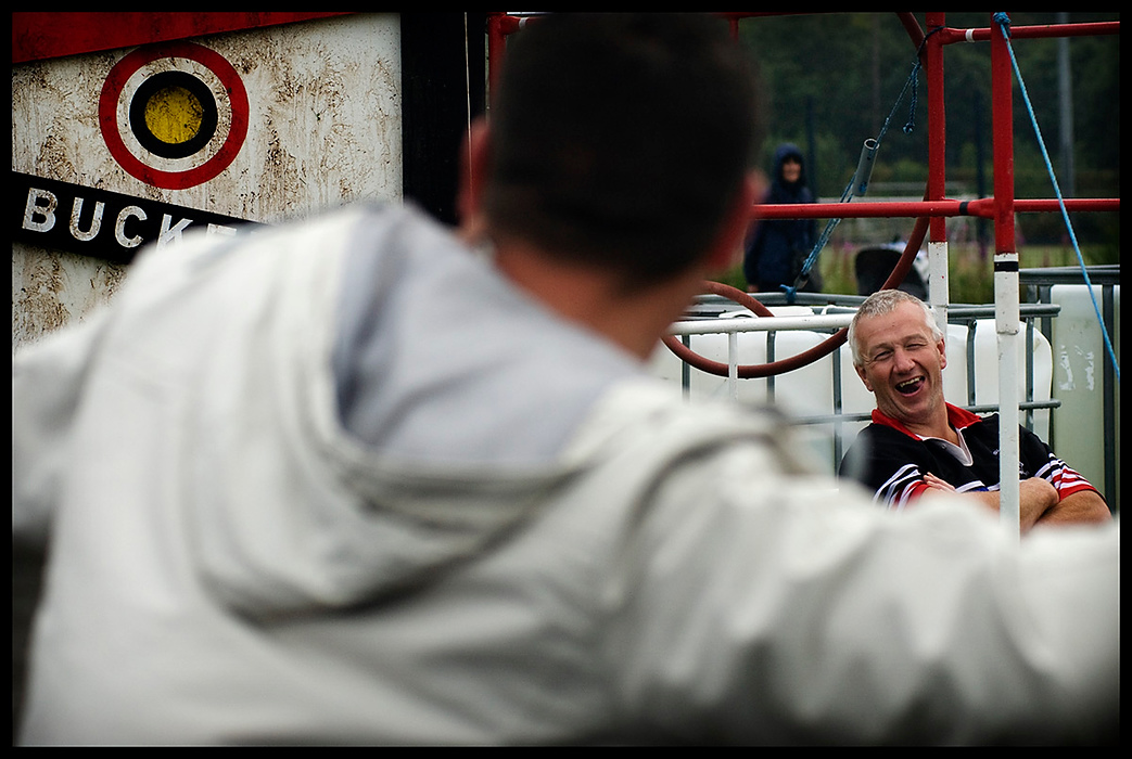 Larry Fullerton Photojournalism Scholarship - James Roh / Ohio UniversityBert Ramage laughs as participants attempt to soak him with water in the bulls eye bucket challenge in Brodick. Participants payed to have a chance to throw tennis balls at the bulls eye which in turn would trigger a bucket full of water to pour upon the person sitting in the chair.  The game was set up at the 2008 Brodick Highland Games as a means to raise funds for the Arran rugby team to play games on the mainland.
