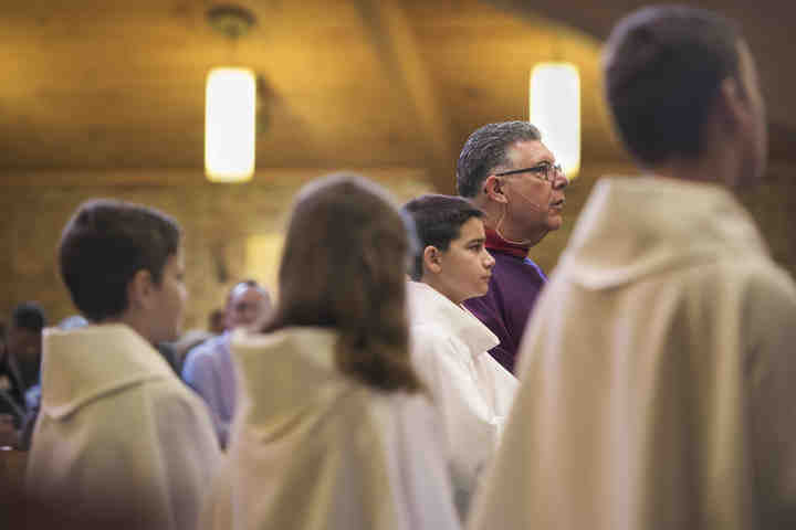 Third place, , Larry Fullerton Photojournalism Scholarsahip - Alexandria Skowronski / Ohio UniversityPastor James M. Daprile, of Youngstown kneels with his alter servers (from left) Peyton Duguay, Katie Sawicki, Zach Best, and Robert Lewandski, all from Aurora, during mass at Our Lady of Perpetual Help Catholic Church in Aurora.  Daprile has been pastor at the parish since January of 2011 and stays involved in the lives of many of its members.  (Alexandria Skowronski/Ohio University)