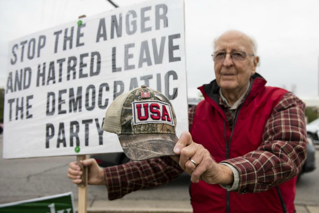 First Place - Larry Fullerton Photojournalism Scholarship , Tanner Pearson / Ohio UniversityBill Corbett holds out his USA hat with one hand and his political sign with the other on Oct. 28, 2020 at the corner of Mason-Montgomery and Escort Dr. in Mason, Ohio. Corbett is a Korean war veteran that supports President Donald Trump because he is seeing how our country is turning towards communism. Corbett states that “Donald Trump is the only one who can save our country.”