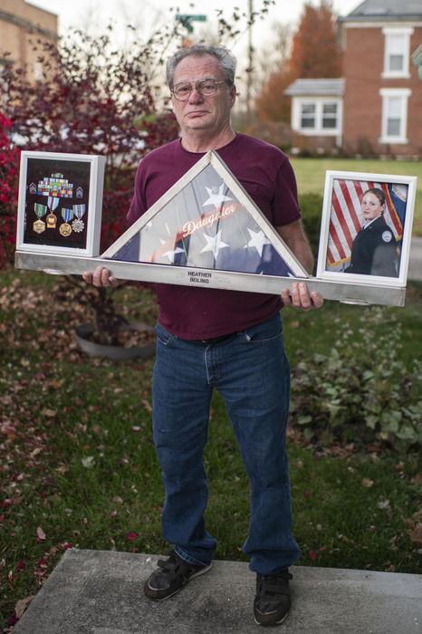 First Place - Larry Fullerton Photojournalism Scholarship , Tanner Pearson / Ohio UniversityJack Boling poses with handcrafted memorabilia display dedicated to his daughter on Nov. 10, 2020. Boling's lost his daughter in 2019 while she was serving in the military. He created this in memory of her.