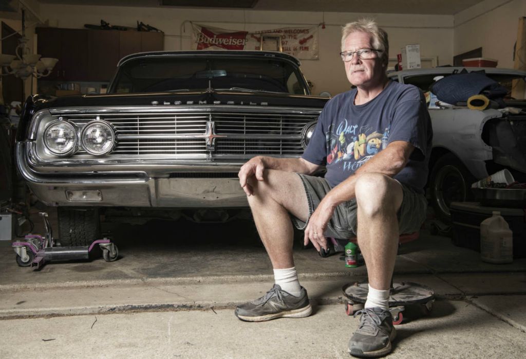 Second Place - Larry Fullerton Photojournalism Scholarship -  Randy Grzybowski, 62 from Seven Hills, Ohio sits next to his newly acquired 1962 Oldsmobile Starfire in his garage next to his son's 1963 Chevy Nova Super Sport. He picked up the Olds to recondition with paint correction and get driving so that he can enjoy it in the future. He has been cars all his life from experiencing there's cars brand new from the early 60s, and into high school owning many cars from Corvettes to Jeeps. (Ryan Grzybowski - Ohio University)  