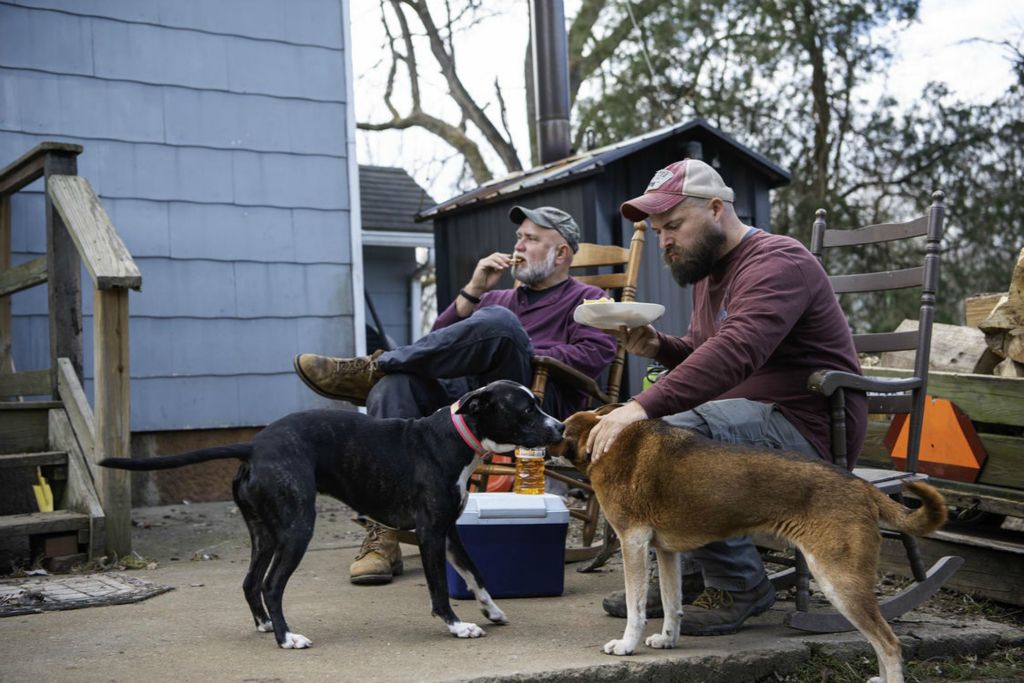 Second Place - Larry Fullerton Photojournalism Scholarship -  Mike and John sit in his backyard for some lunch after moving the goats while petting his two dogs and enjoying the day and taking a midday break from all the work the two have done. (Ryan Grzybowski - Ohio University)  