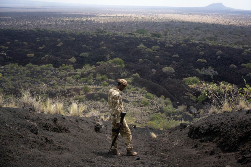 First Place - Larry Fullerton Photojournalism Scholarship -  Musa, 27, a park ranger, leads a hike down the Chaimu Crater in Tsavo West National Park, Kenya, on July 16, 2021. “I’ve used my rifle a few times … only to scare away animals, never to kill,” said Musa. The volcano was named Chaimu or “a place of the ghosts,” 150 years ago when it last erupted. (Joe Timmerman - Ohio University)  