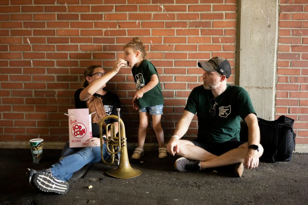 First Place - Larry Fullerton Photojournalism Scholarship -  An Ohio University Marching 110 alumni couple takes a moment in the shade with their daughter as the Bobcats football team plays Central Michigan at Peden Stadium in Athens on October 9, 2021. (Joe Timmerman - Ohio University)  