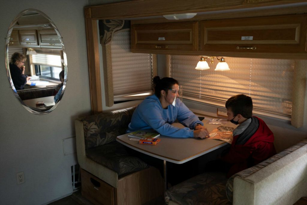 First Place - Larry Fullerton Photojournalism Scholarship -  Evangeline DeVol, the founder of an RV-based learning program called NEST, is reflected in the mirror while sifting through paperwork as Lacy Walker, a paid tutor and teacher at a local high school, works with a fourth grader inside the RV in Batavia, Ohio, on Oct. 21, 2020. NEST is based in Loveland, Ohio, about 30 minutes west of Batavia, and as the program continues to grow, and face on-going challenges with the COVID-19 pandemic, DeVol is looking for Walker and other volunteers to take on more responsibilities. (Joe Timmerman - Ohio University)  