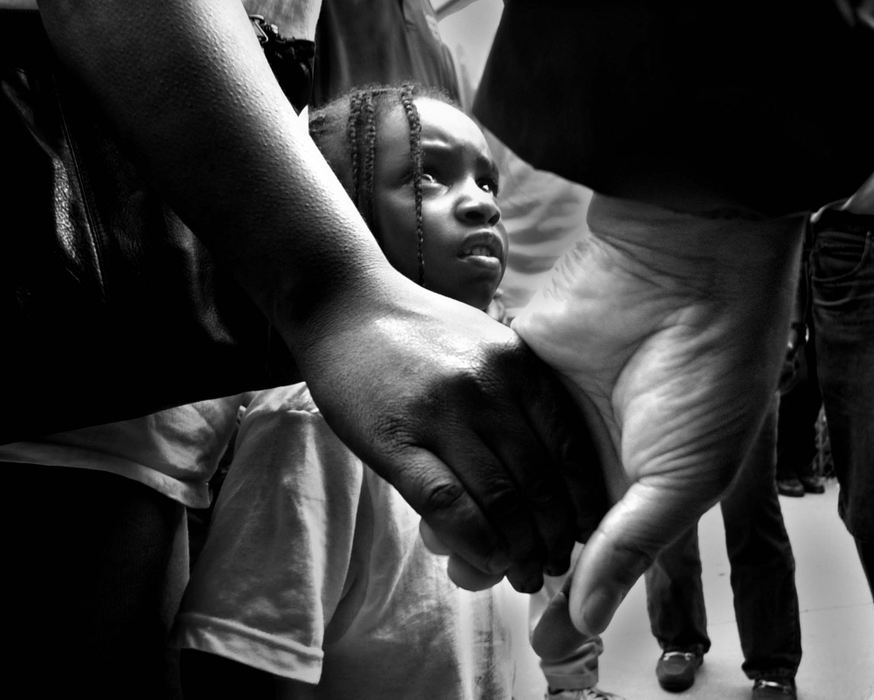 First Place, Assigned Feature - Michael E. Keating / Cincinnati EnquirerCaught in the middle of difficult times Ron-Autica Sutton looks upward at a white man holding her mother's hand during a prayer service as ministers, activists and volunteers took to the streets to preach and plead for peace as Cincinnati endured a second day of civil unrest Apil 11, 2001. 