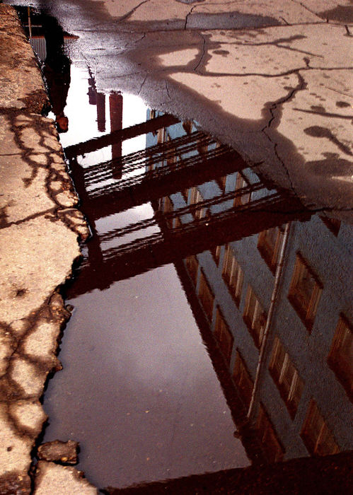 Second Place, Feature Picture Story - Mike Levy / The Plain DealerA worker is reflected in a puddle along with a few of the towering smoke stacks of the Martin furnace at Severstal. 