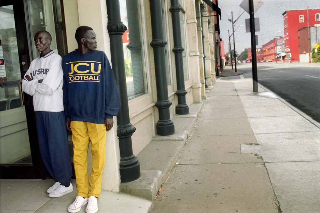 Award of Excellence, Feature Picture Story - Lynn Ischay / The Plain DealerIn canvas sneakers and secondhand clothes, Peter Awol (left) and Peter Alier wait on the common threshold for refugees to America, the Social Security office. On his first morning in Cleveland, Alier watches for danger, and for cars, already wondering when he will get a chance to drive. 