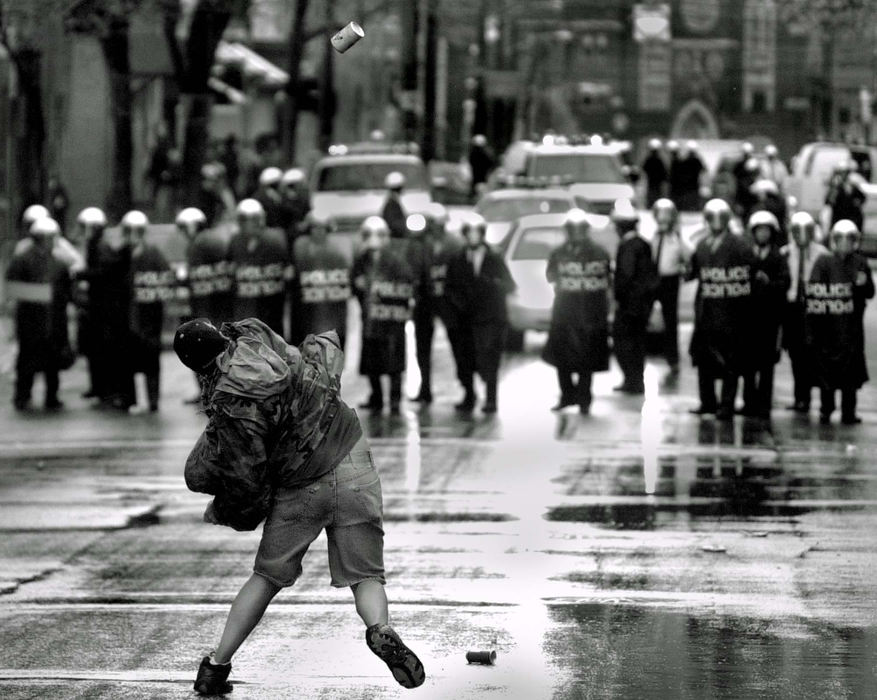 Second Place, News Picture Story - Michael E. Keating / Cincinnati Enquirer A single protestor tosses a can of fruit toward a police line as police gather to begin rounding up protestors in the streets. Marchers too to the streets after Cincinnati Police killed an unarmed man they were pursuing.