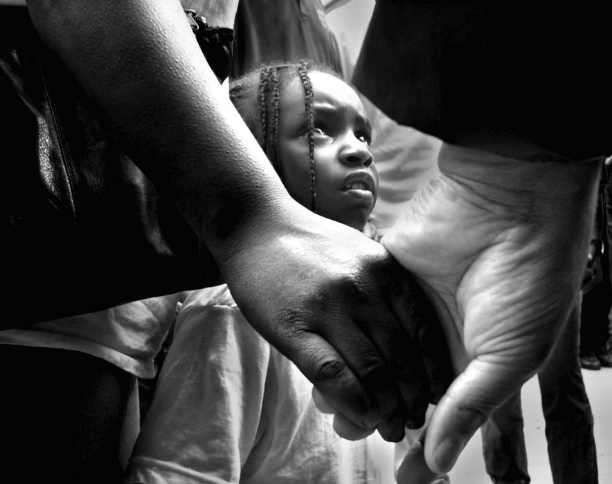 Second Place, News Picture Story - Michael E. Keating / Cincinnati EnquirerCaught in the middle of difficult times Ron-Autica Sutton -4- looks upward toward a white man holding the hand of her mother during a prayer service as ministers, activists and volunteers took to the streets to preach and plead for peace as Cincinnati endured riots in the streets.