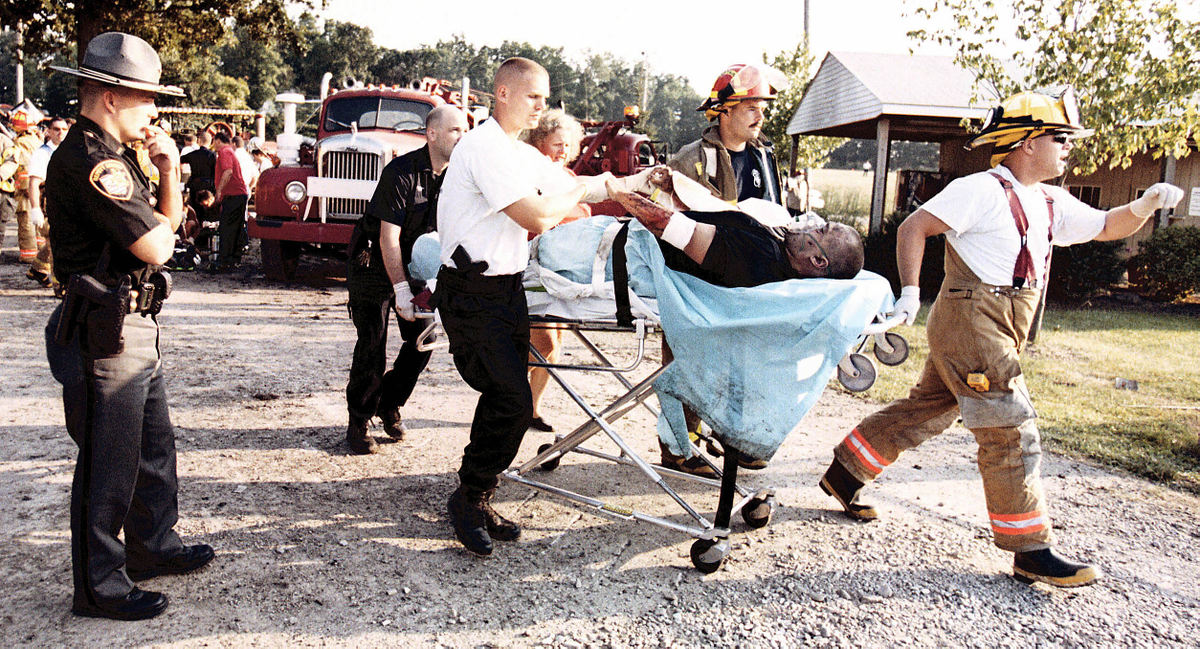 Third Place, News Picture Story - Shirley Ware / The Medina GazetteTwo police officers were injured in the blast at the Medina County Fairgrounds. A Medina CountySherif (left) watches as a fellow law enforcement officer is rushed from the site to a waiting medic helicopter.