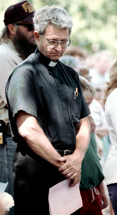 Third Place, News Picture Story - Shirley Ware / The Medina GazetteFather Ron Bryda gazes at the ground during a memorial prayer service for the victims of the steam engine explosion. The service was set up by area churches in response to the explosion of an antique steam engine at the Medina County Fair that killed 5 and injured 50.  