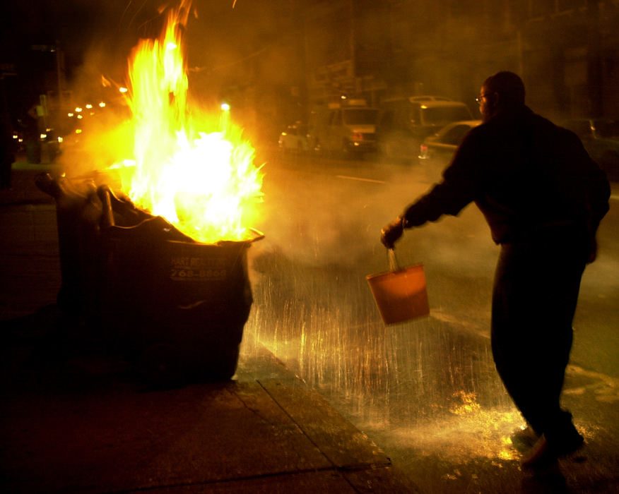 Award of Excellence, News Picture Story - Brandi Stafford / The Cincinnati EnquirerMujahid Abdul throws water on a dumpster fire set by protestors angry over the not guilty verdict given to Cincinnati Police Officer Stephen Roach for the shooting death of an unarmed black man. 