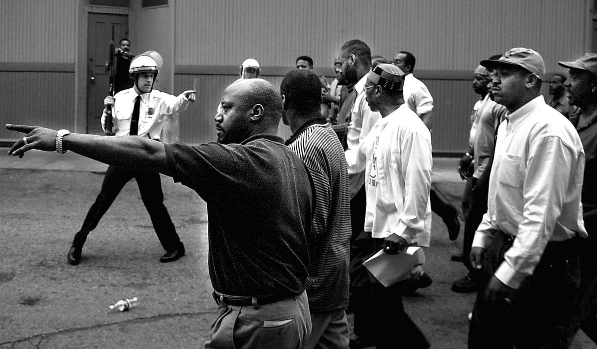 First Place, News Picture Story - Steven M. Herppich / Cincinnati EnquirerCincinnati Police confront members of the New Prospect Baptist Church on Elm Street near Findlay market Tuesday night. Protestors rioted throughout the day into the night burning and destroying businesses as well as attacking both police and civilians. The shooting of Timothy Thomas lead to one week of protests, riots, and a city imposed curfew leading up to the funeral of this 19-year-old man.