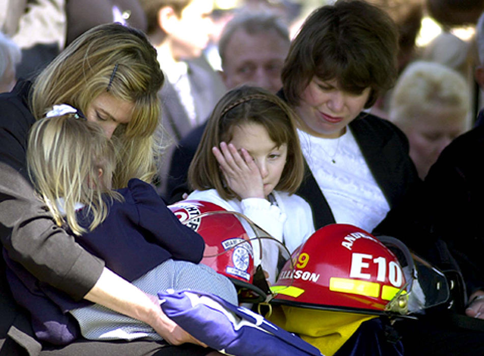 Award of Excellence, News Picture Story - Glenn Hartong / The Cincinnati EnquirerWife Victoria Ellison and her daughters Michaela 5, and Marissa 8, mourn at the graveside during firefighter/paramedic William "Doc" Ellison's burial at St. Stephen Cemetery in Fort Thomas Kentucky. They hold the flag and the helmets given to them by both Miami and Anderson Townships where he was a firefighter.