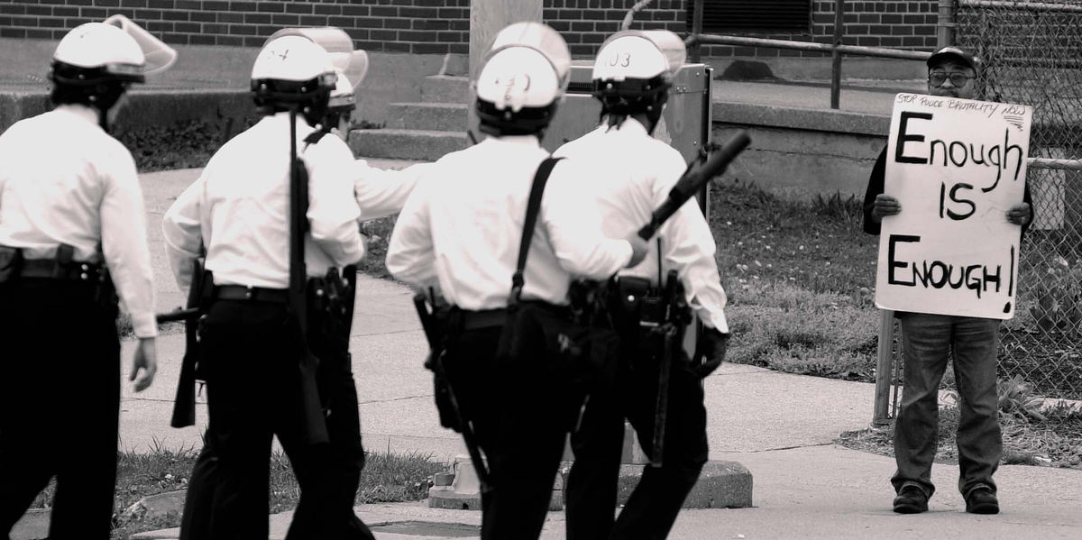 Third Place, Photographer of the Year - Michael E. Keating / Cincinnati EnquirerAs a riot squad of police move into a neighborhood a lone protestor stands on a street corner in silent protest of alleged police abuses. Questions of police training and actions launched a US Dept. of Justice investigation.