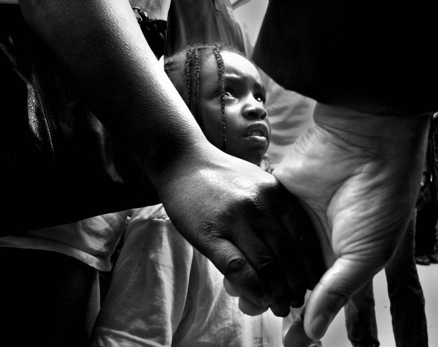 Third Place, Photographer of the Year - Michael E. Keating / Cincinnati EnquirerCaught in the middle of difficult times Ron-Autica Sutton -4- looks upward toward a white man holding the hand of her mother during a prayer service as ministers, activists and volunteers took to the streets to preach and plead for peace as Cincinnati endured riots in the streets.