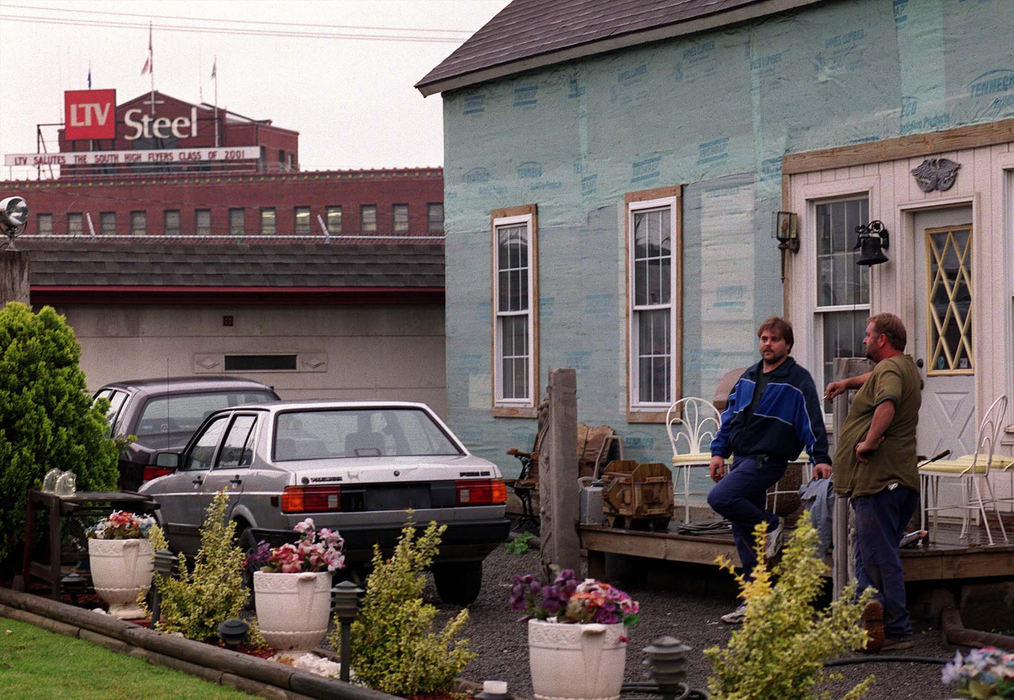 First Place, Photographer of the Year - Mike Levy / The Plain DealerChris Maynard chats in the backyard of Charles Piazza who lives on Lester. His backyard helps frame the LTV steel sign.