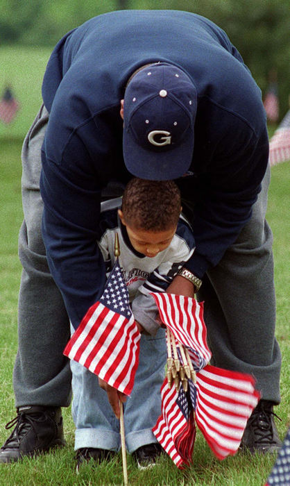 First Place, Photographer of the Year - Mike Levy / The Plain DealerRobert Fitzpatrick, who manages a recreation center in Cleveland, helps his son, Chris, 3, place a flag yesterday at the grave of a veteran buried at Cleveland's Highland Park Cemetery at Chagrin Blvd. and Northfield Rd. Cub Scouts, children from Cleveland recreation centers and other groups are placing more than 20,000 flags at the cemetery for Memorial Day this Monday.