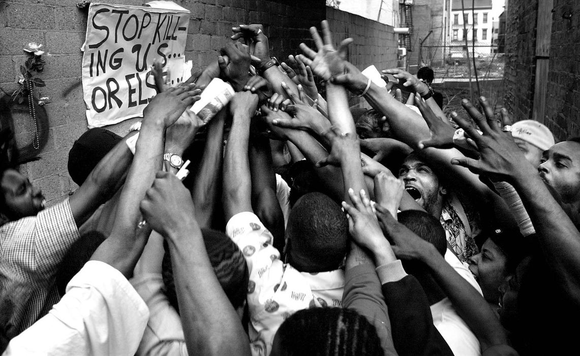 Second Place, Photographer of the Year - Steven M. Herppich / Cincinnati EnquirerProtestors gather at the scene of the fatal police shooting of Timothy Thomas where a  memorial has been place in the alleyway by Republic Street in Over-the-Rhine. Thomas was shot and killed by a Cincinnati Police officer, April 7, 2001. The shooting lead to one week of protests, riots, and a city imposed curfew leading up to the funeral of this 19-year-old man.