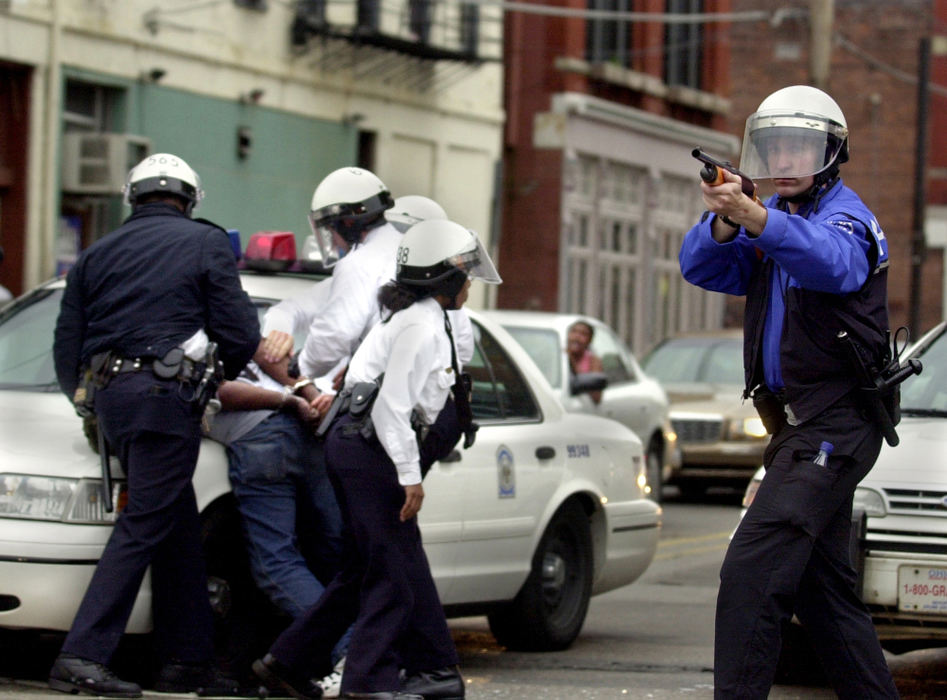 Award of Excellence, Spot News Large Market - Gary Landers / Cincinnati EnquirerA man (left) is arrested by Cincinnati Police Officers at the corner of 12th and Vine Streets in Cincinnati's Over-the-Rhine area for refusing to disperse. A police officer (right) fires non-lethal beanbag projectiles into a crowd during civil unrest brought about by Cincinnati Police Officer Steve Roach shooting and killing an unarmed black man, Timothy Thomas.