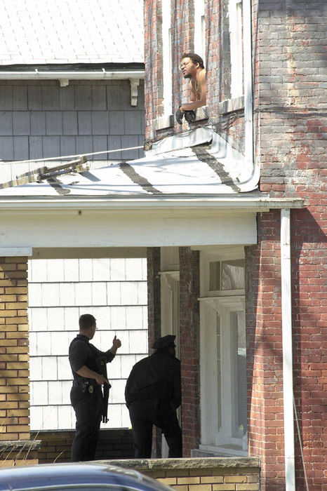 Award of Excellence, Spot News Small Market - Kyle Lanzer / The Alliance ReviewEmmett "Earl" Taylor Jr. leans out of his apartment window at 336 E. Broadway St. during a two hour standoff as Alliance City police officers cautiously approach the front door of the six unit building. 