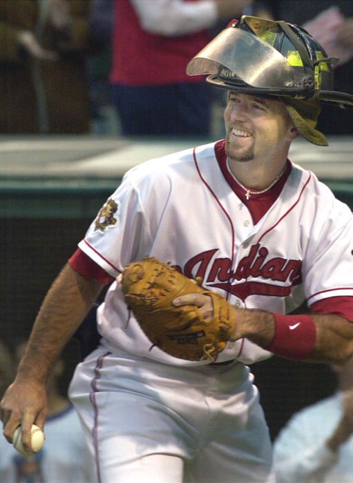 Second Place, Sports Picture Story - Chuck Crow / The Plain DealerIndians catcher Ed Taubensee, wearing a Cleveland firefighter helmet, looks back to the pitchers mound after Cleveland Police Officer John Fore let loose with a wild pitch.  A Cleveland police officer, firefighter and EMS paramedic each threw out a first pitch, in honor of the heroic work of their brothers in New York City.  This was the first game at Jacobs Field since the terror strikes hit the USA.  