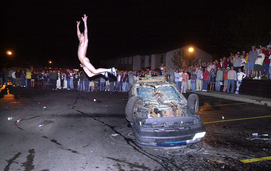 Second Place, Team Picture Story - Phil Masturzo / Akron Beacon journalA nude revler leaps from atop of an overturned car as hundreds of students look on. 