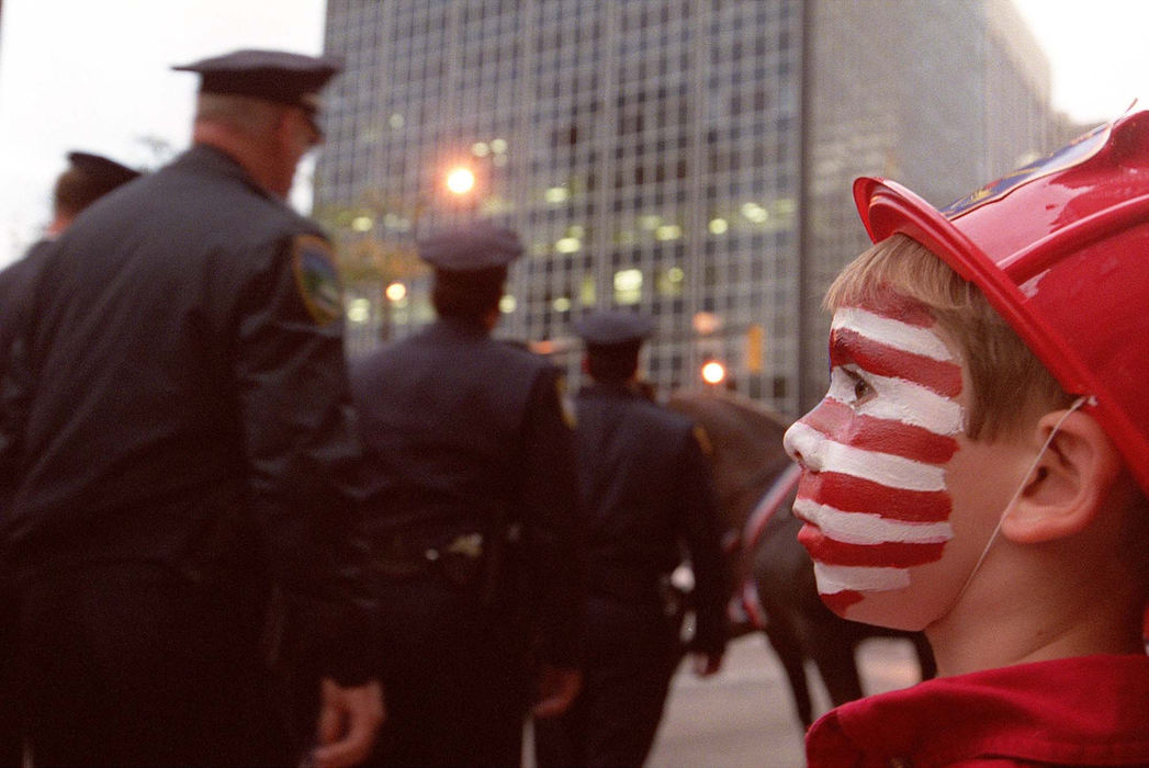 Third Place, Team Picture Story - Mike Levy / The Plain DealerFive-year-old Isaac Scuvott of Bedford watches the procession of firefighters and police officers as they march down E. 9th Street  towards Cleveland's St. John's Cathedral on Sept. 17.  