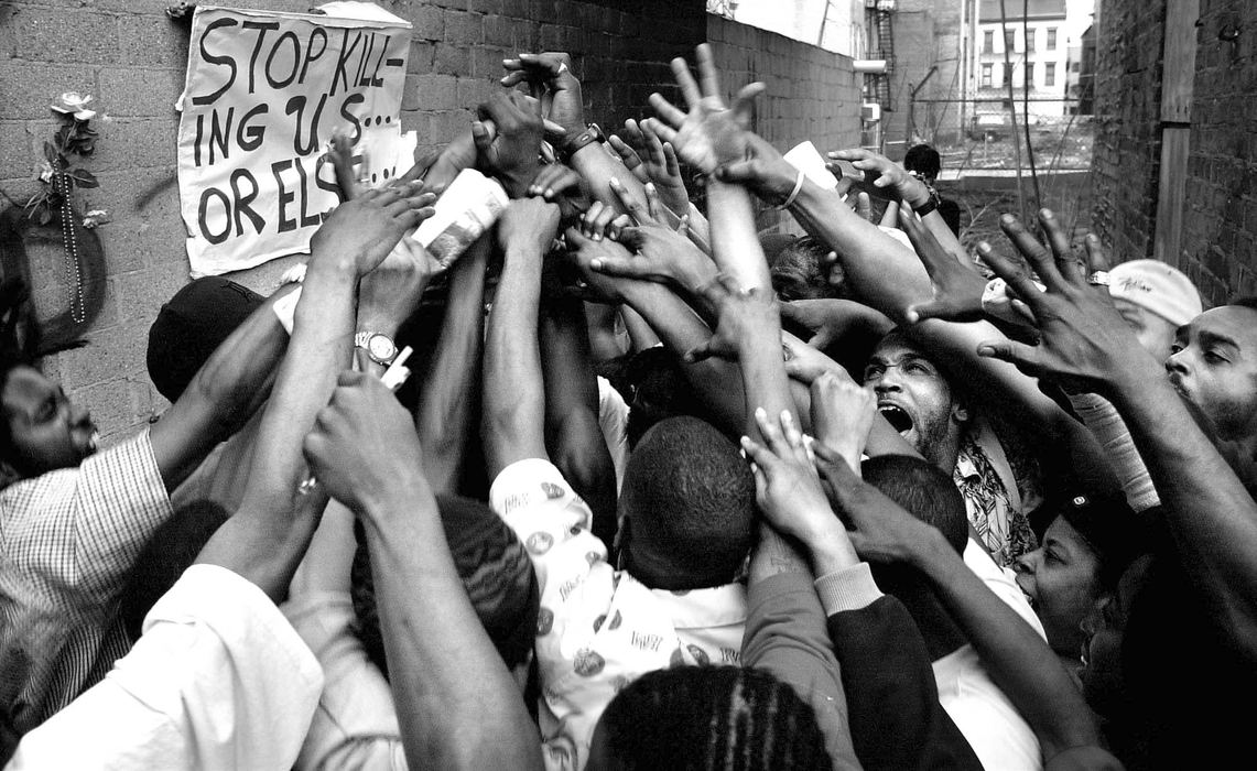 First Place, Team Picture Story -  / Cincinnati EnquirerProtestors gather at the scene of the fatal police shooting of Timothy Thomas where a  memorial has been place in the alleyway by Republic Street in Over-the-Rhine. Thomas was shot and killed by a Cincinnati Police officer April 7, 2001. The shooting lead to one week of protests, riots, and a city imposed curfew leading up to the funeral of this 19-year-old man.